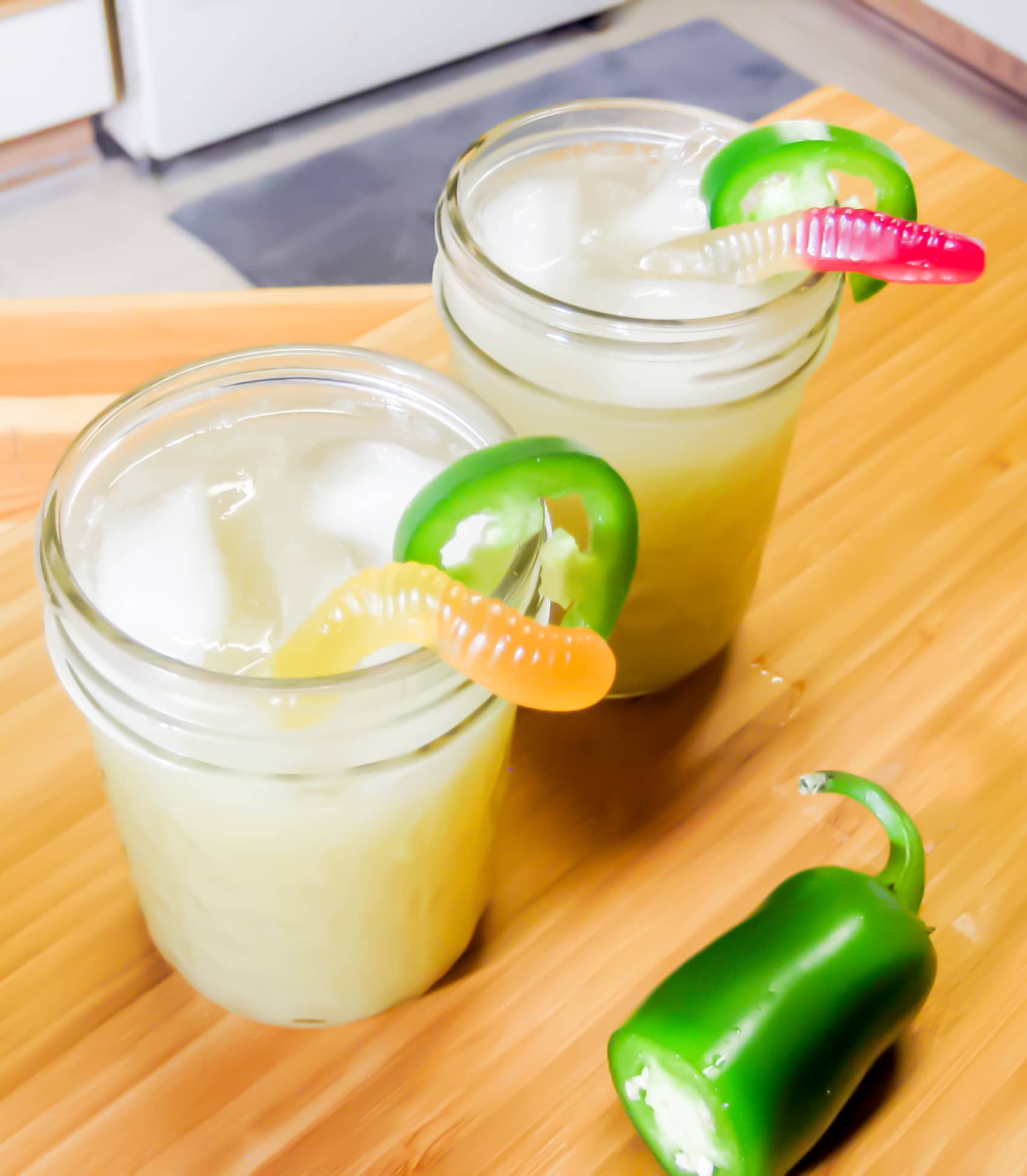 Photo of 2 margaritas garnishe with gummy worms and jalapenosd 